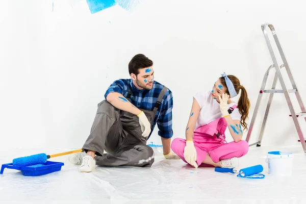 Novio y novia sentado en el suelo en la habitación con reparaciones - foto de stock