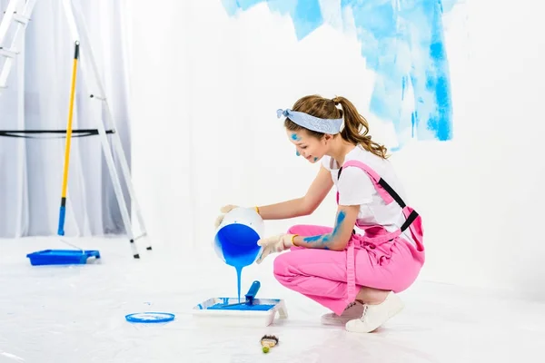 Menina derramando tinta de balde em bandeja de pintura de plástico — Fotografia de Stock