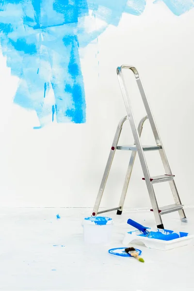 Escalera y pincel rodillo de pintura en pintura azul - foto de stock