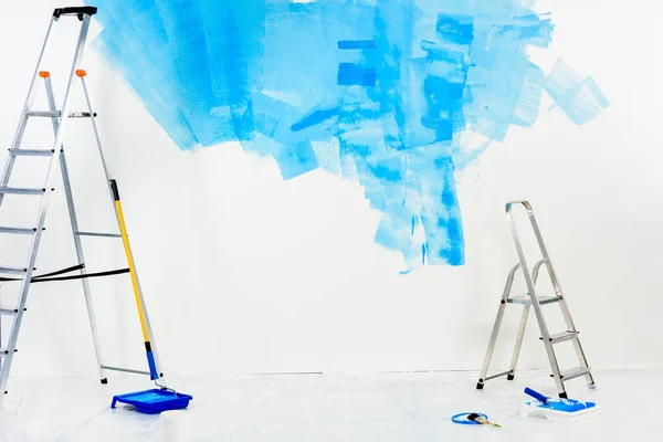 Escadas e pincéis de rolo de pintura em tinta azul — Fotografia de Stock
