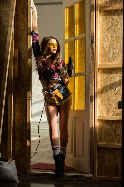 Sexy girl posing with electric drill on construction — Stock Photo