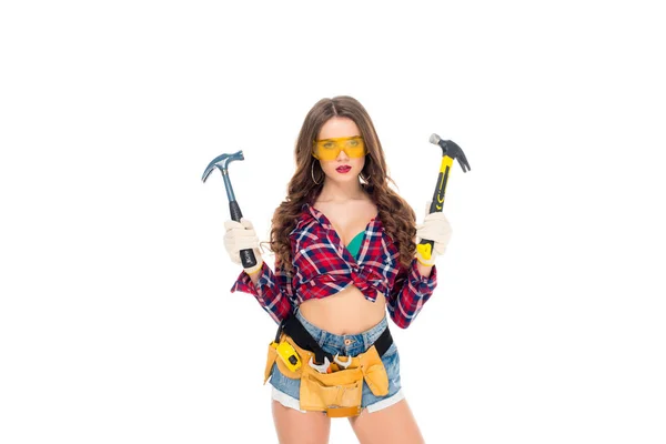 Beautiful girl in goggles and gloves with tool belt holding hammers, isolated on white — Stock Photo