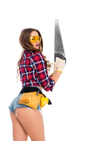 Attractive girl in goggles with tool belt holding saw, isolated on white — Stock Photo