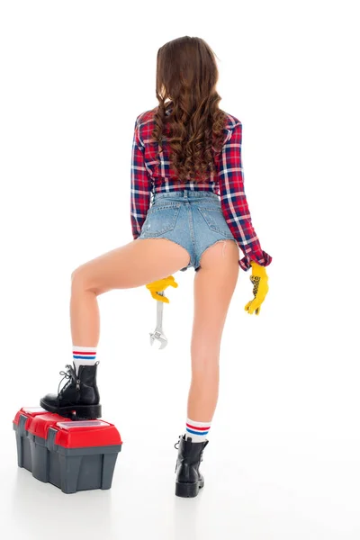 Vista trasera de chica sexy posando con caja de herramientas y llave inglesa, aislado en blanco - foto de stock