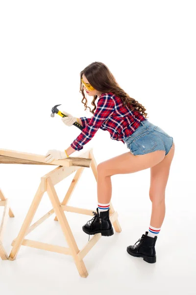 Sexy brunette girl in goggles working with hammer, isolated on white — Stock Photo