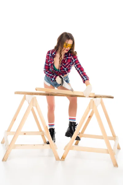 Verführerisches Mädchen in Brille, das mit Säge arbeitet, isoliert auf weiß — Stockfoto