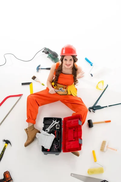 Overhead view of girl in overalls sitting on floor with toolbox and different equipment, isolated on white — Stock Photo