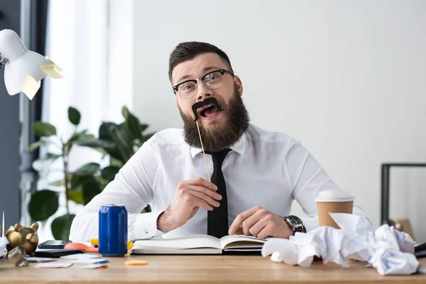 Ritratto di allegro uomo d'affari con decorazione di partito seduto sul posto di lavoro in ufficio — Foto stock