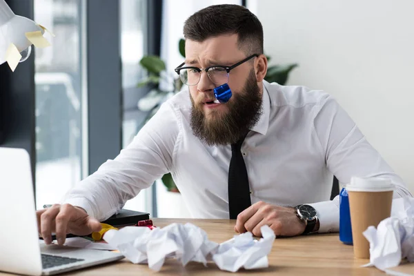 Portrait of businessman with party decoration working on laptop at workplace in office — Stock Photo