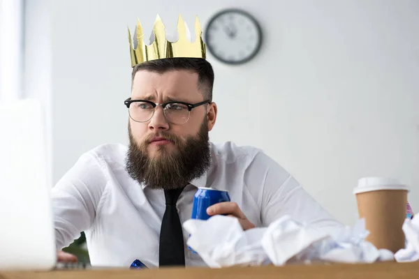 Retrato de homem de negócios com coroa de papel na cabeça e bebida com gás no local de trabalho no escritório — Fotografia de Stock