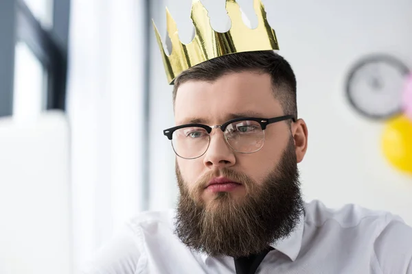 Portrait of bearded businessman in eyeglasses with paper crown on head — Stock Photo