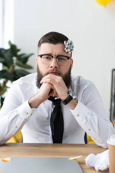 Portrait of thoughtful businessman with bow on head at workplace in office — Stock Photo