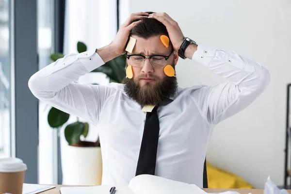 Retrato de empresário cansado em desgaste formal com notas pegajosas no rosto no local de trabalho no escritório — Fotografia de Stock