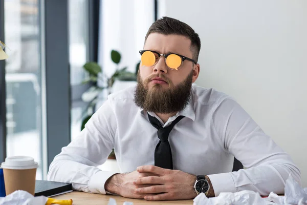 Porträt eines Geschäftsmannes mit Haftnotizen an der Brille am Arbeitsplatz im Büro — Stockfoto