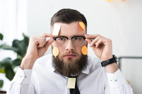 Portrait d'homme d'affaires en lunettes avec des notes collantes sur le visage au bureau — Photo de stock