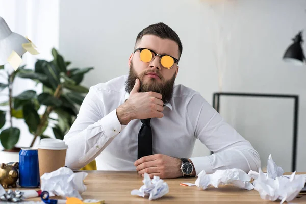 Портрет бизнесмена с липкими заметками на очках на рабочем месте в офисе — стоковое фото