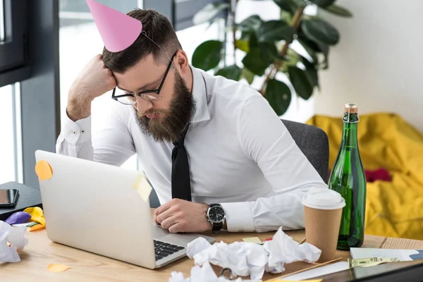 Homme d'affaires avec cône en papier sur la tête dormant sur le lieu de travail — Photo de stock