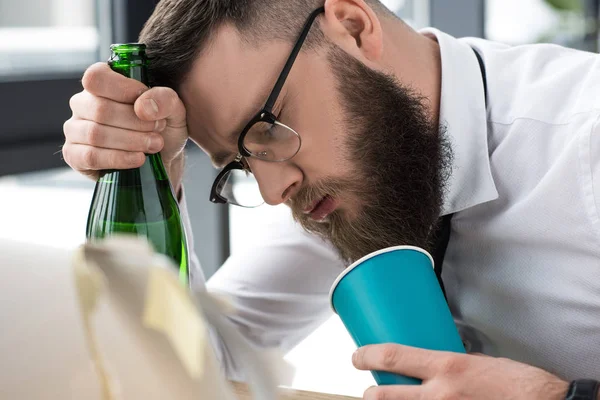 Drunk businessman with bottle of champagne sleeping at workplace — Stock Photo