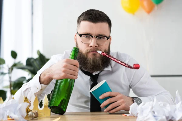 Portrait of businessman in formal wear with bottle of champagne at workplace in office — Stock Photo