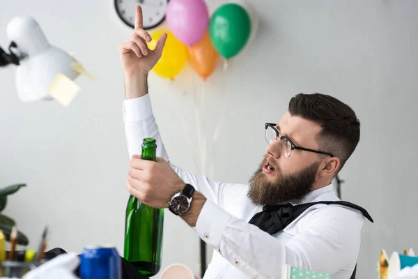 Empresário com garrafa de champanhe sentado no local de trabalho no escritório — Fotografia de Stock