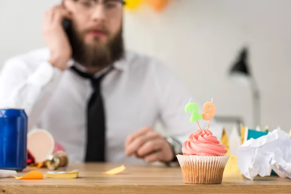 Foco seletivo de cupcake aniversário e homem de negócios no local de trabalho — Fotografia de Stock