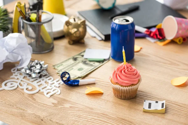 Close up view of birthday cupcake with candle and party decorations at workplace — Stock Photo