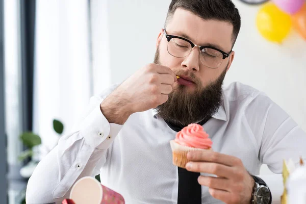 Portrait de l'homme d'affaires tenant cupcake d'anniversaire dans les mains dans le bureau — Photo de stock