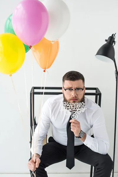 Retrato de homem de negócios em desgaste formal com sinal de aniversário feliz e balões — Fotografia de Stock