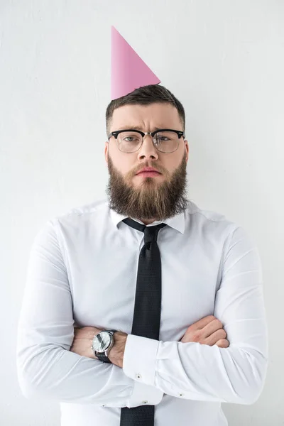 Portrait of bearded businessman in formal wear and with party cone on head isolated on grey — Stock Photo