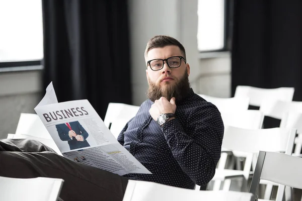 Retrato de homem de negócios barbudo pensivo com jornal sentado na sala de reuniões — Fotografia de Stock