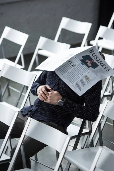 Частичный взгляд бизнесмена, спящего с газетой на лице во время сидения в зале заседаний — стоковое фото
