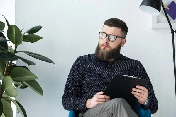 Porträt eines nachdenklichen Geschäftsmannes mit Notizblock, der wegschaut — Stockfoto