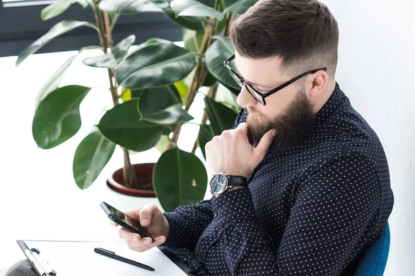 Side view of businessman with notepad using smartphone — Stock Photo