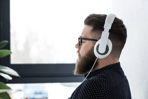 Side view of man with eyes closed listening music in headphones — Stock Photo