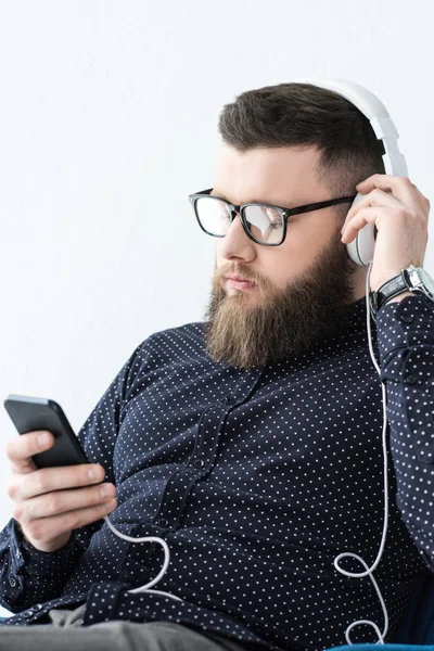 Porträt eines Mannes mit Smartphone, der Musik im Kopfhörer hört — Stockfoto