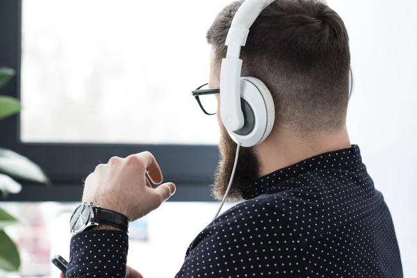Vista parcial del hombre con smartphone escuchando música en auriculares - foto de stock