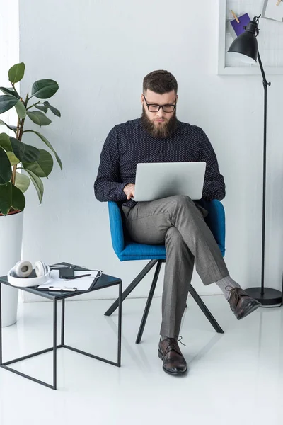 Uomo d'affari concentrato che lavora su computer portatile in sedia — Foto stock