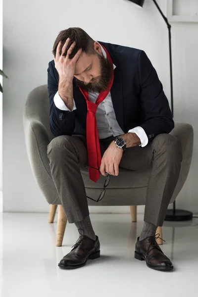 Hombre de negocios sobrecargado de trabajo en traje elegante sentado en sillón - foto de stock