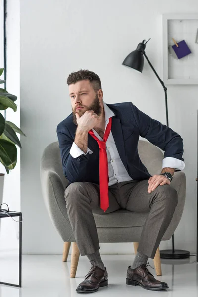 Вдумчивый бизнесмен в костюме сидит в кресле — стоковое фото