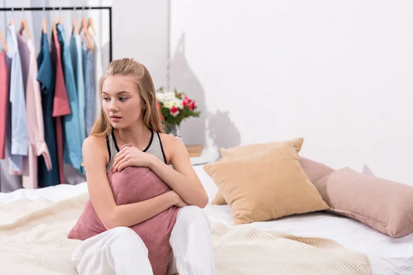 Schöne junge Frau sitzt im Bett und umarmt Kissen — Stockfoto