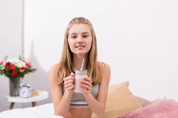 Bela jovem mulher com pedreiro frasco de milkshake olhando para a câmera — Fotografia de Stock