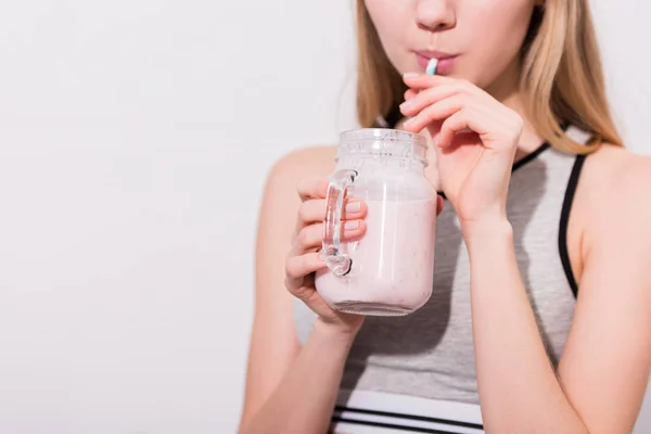 Tiro cortado de jovem mulher bebendo milkshake de pote de pedreiro com palha — Fotografia de Stock