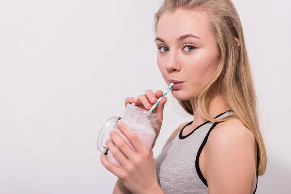 Schöne junge Frau trinkt Milchshake aus Einmachglas mit Stroh — Stockfoto