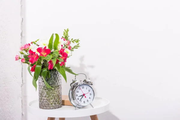 Винтажный будильник на столе с цветами в вазе — стоковое фото