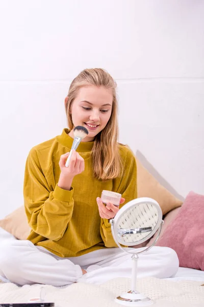 Happy young woman applying blush — Stock Photo