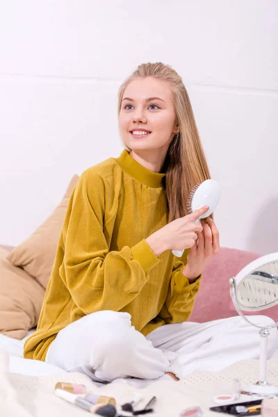 Jovem mulher feliz escovando o cabelo em casa — Fotografia de Stock