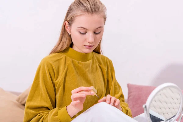 Attraktive junge Frau, die zu Hause im Bett Nägel poliert — Stockfoto