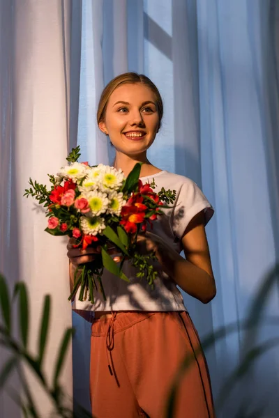 Giovane donna con bel bouquet contro la finestra — Foto stock