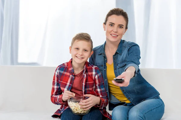 Feliz madre e hijo viendo la televisión junto con palomitas de maíz - foto de stock