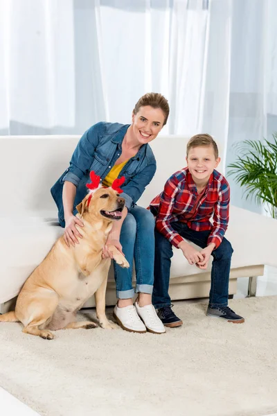 Mãe e filho acariciando seu cão em casa — Fotografia de Stock